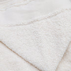Gros plan sur l'éponge coton longues fibres et la bordure point de croix d'une cape de bain bébé fabrication portugaise