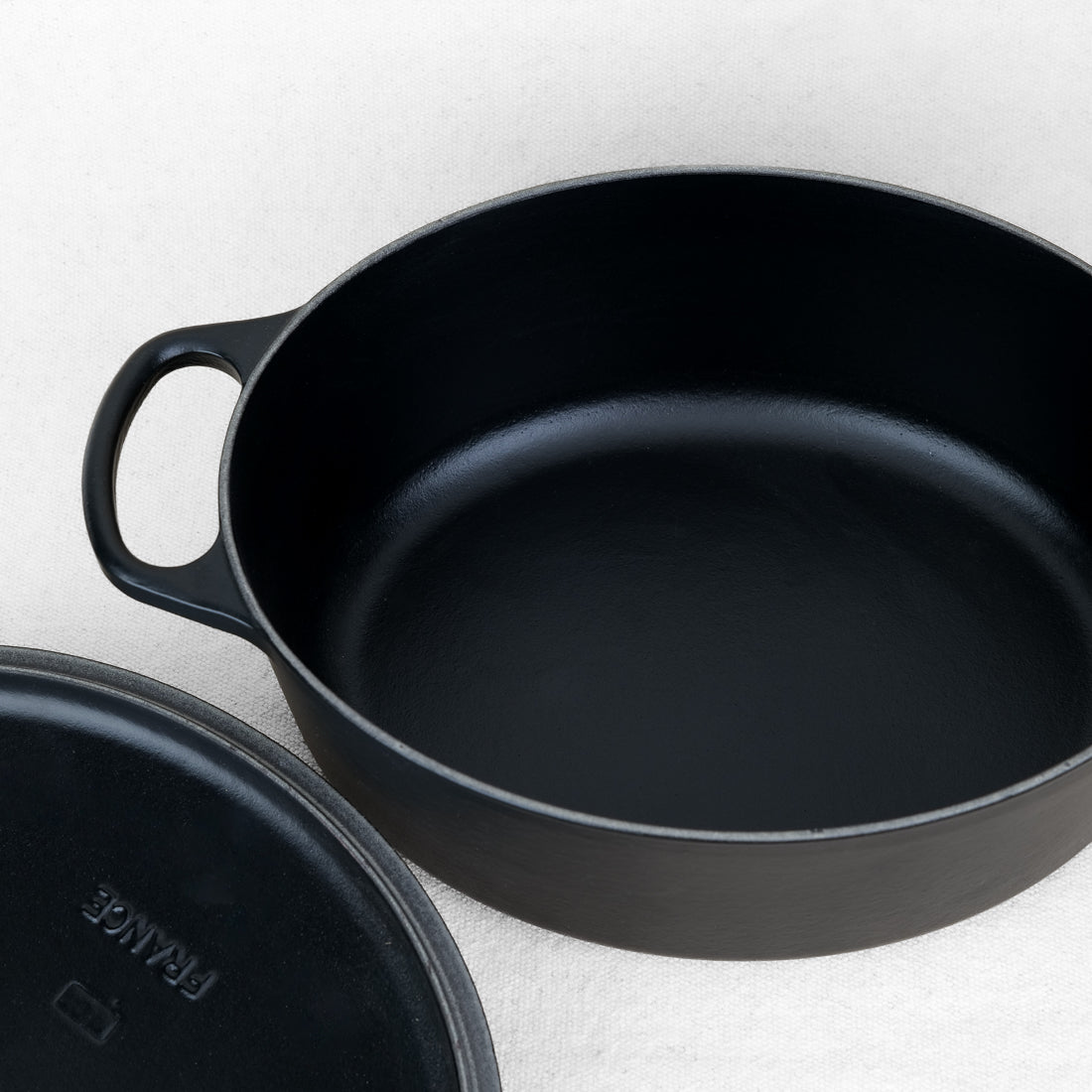 Intérieur de la cocotte ovale Le Creuset en fonte émaillée noir mat, couvercle posé à côté, fabrication française