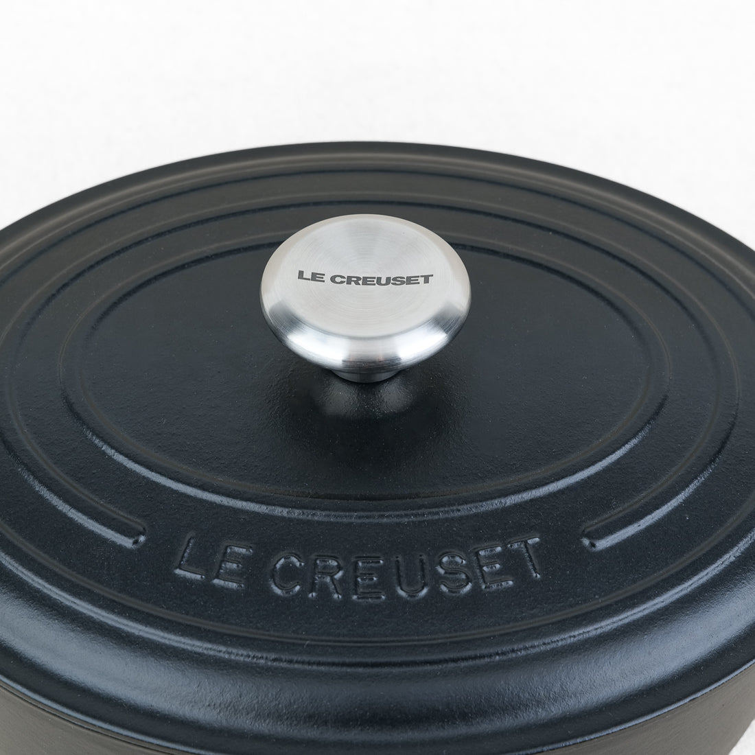 Gros plan sur le couvercle et le bouton inox de la cocotte ovale Le Creuset en fonte émaillée noir mat, fabrication française