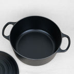 Intérieur de cocotte ronde Le Creuset en fonte émaillée noir mat, fabrication française, couvercle posé à côté