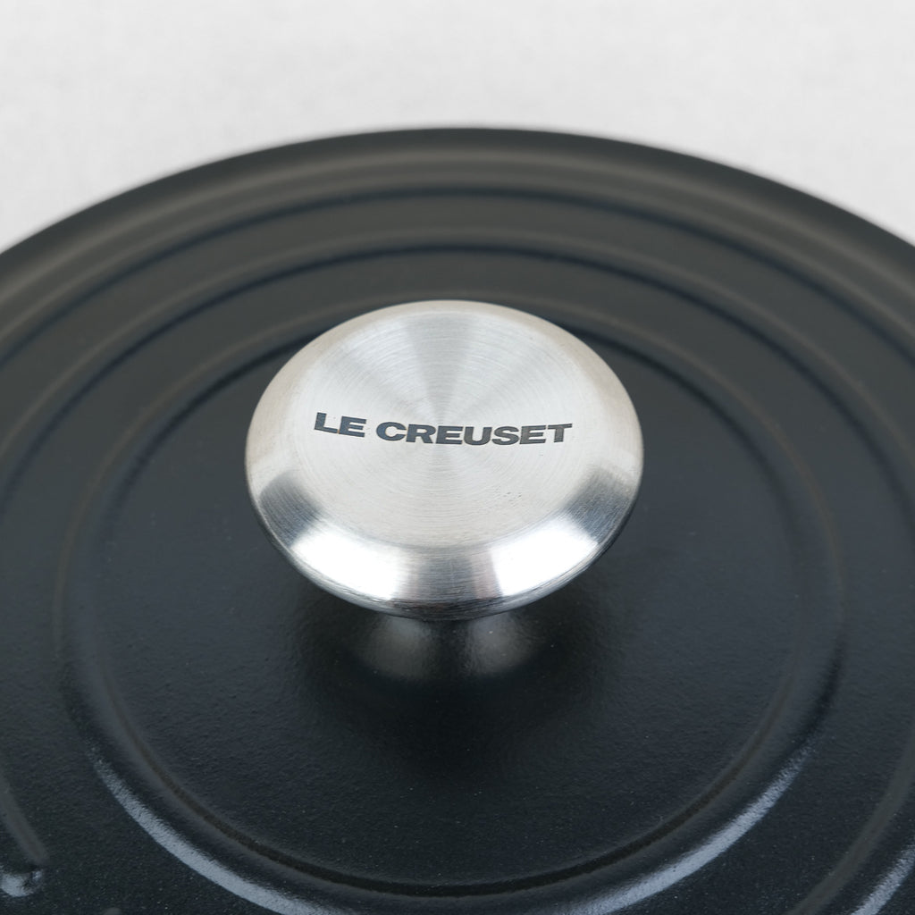 Bouton inox gravé Le Creuset sur couvercle de cocotte ronde en fonte émaillée noir mat, fabrication française