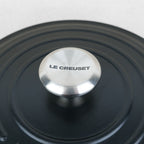 Bouton inox gravé Le Creuset sur couvercle de cocotte ronde en fonte émaillée noir mat, fabrication française