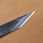 Gros plan sur le tranchant biseauté et la surface martelée Tsuchime du couteau de marquage kiridashi en acier forgé Takagi