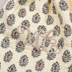 Gros plan sur le monogramme brodé beige d'une housse de bouillotte provençale Empereur en coton matelassé crème