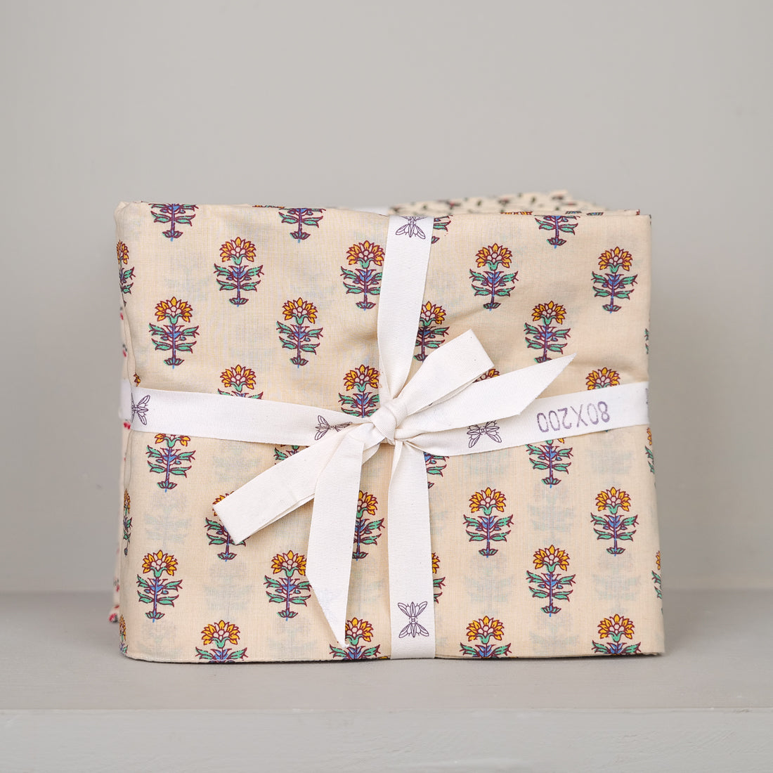Eiderdown cover 85x200 cm in artisan block-printed cotton, hand-printed floral pattern, shown folded and tied with ribbon
