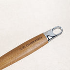 Gros plan sur le manche en bois gravé Le Creuset avec anneau inox de la sauteuse fonte émaillée 28 cm fabrication française