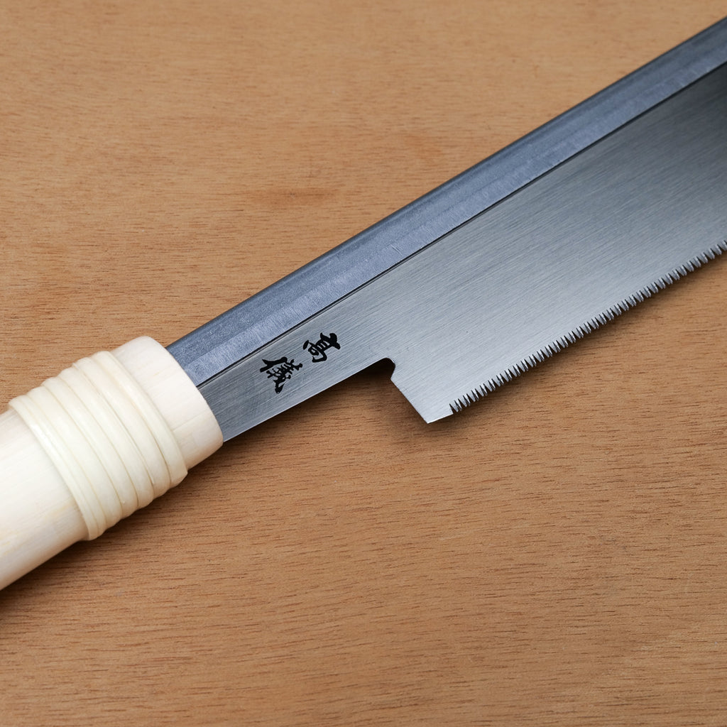 Gros plan sur la lame et les dents fines d'une scie Dozuki japonaise Takagi, trait de coupe 0,3 mm pour marqueterie
