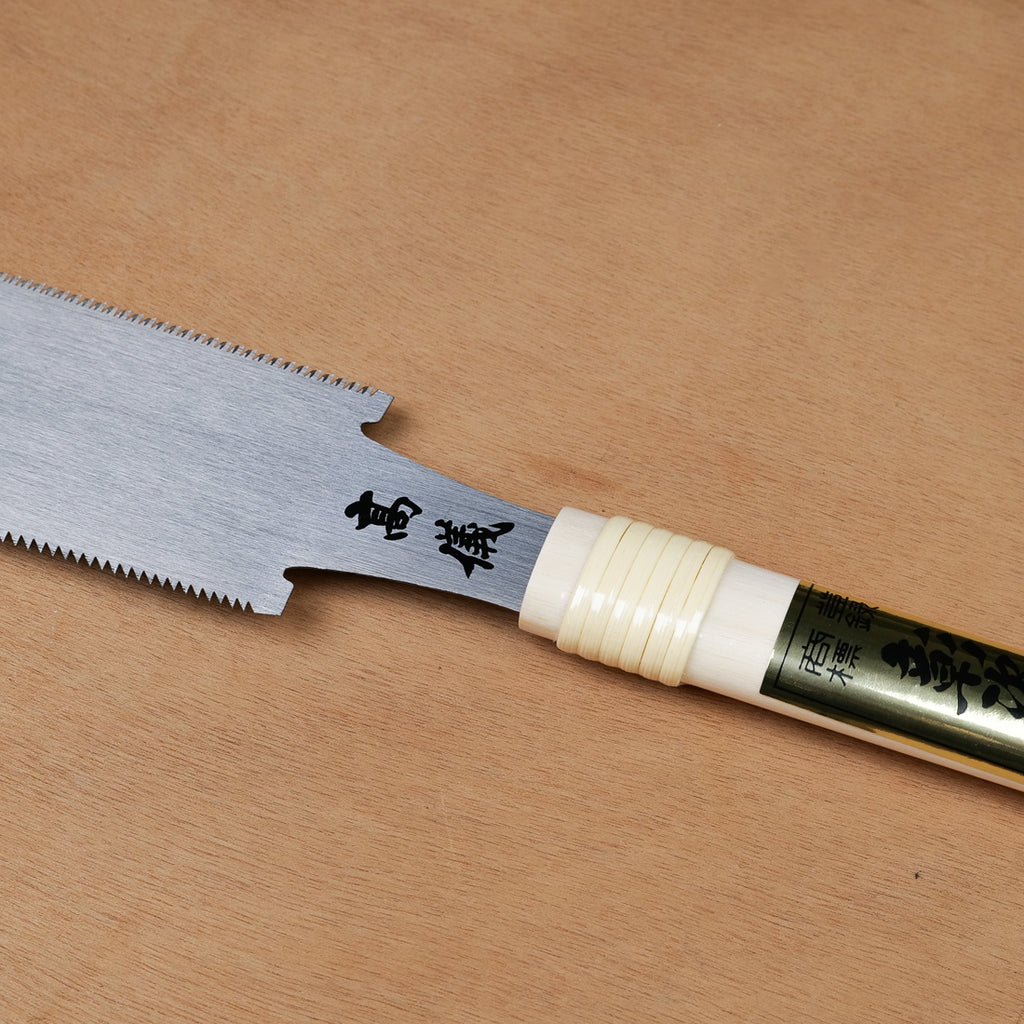 Gros plan sur la lame évidée et le manche de la scie à tirer Ryoba premium Takagi, fabrication japonaise