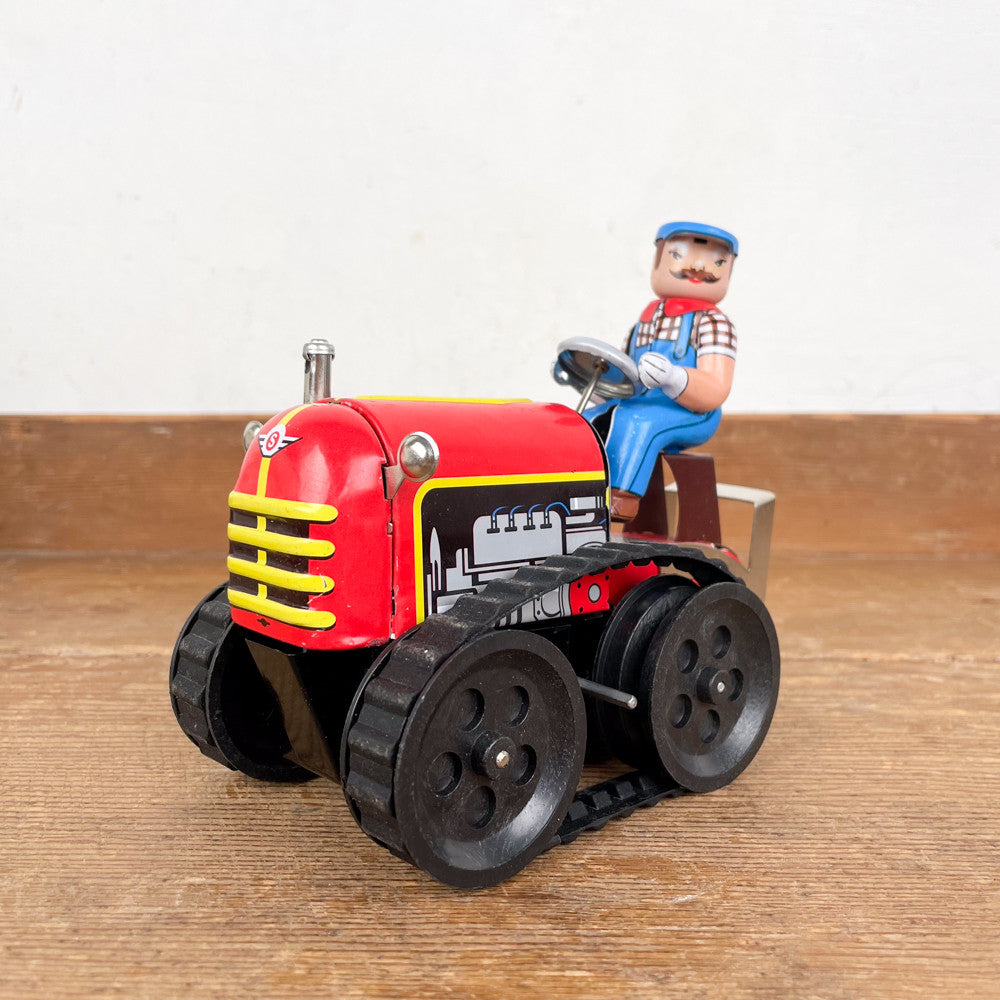 Tracteur mécanique rouge et son chauffeur