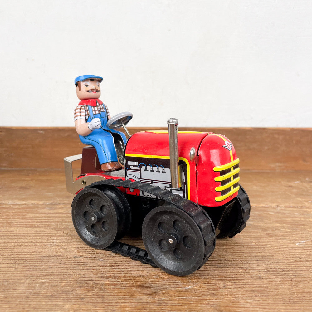 Tracteur mécanique rouge et son chauffeur