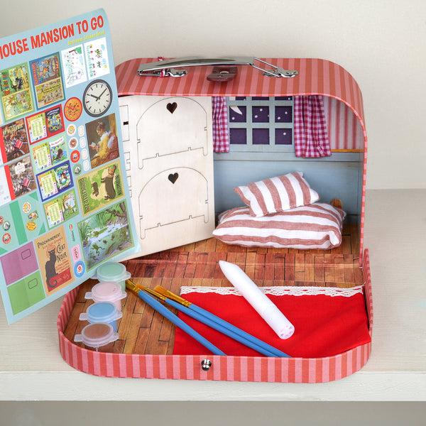 Valise carton chambre d'enfant à monter et décorer, ouverte sur une chambre miniature avec coussins et rideaux